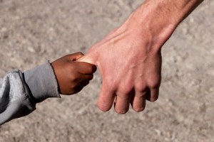 Flüchtlingskind an Hand eines Helfers
